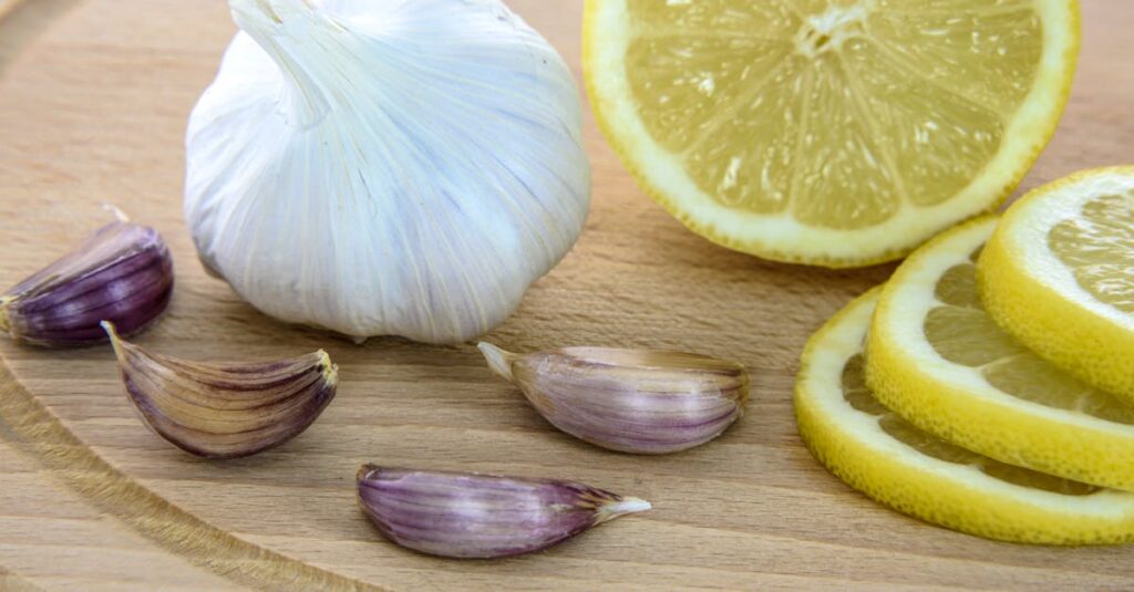 Close-up of fresh garlic and lemon slices on a wooden board, ideal for healthy cooking.