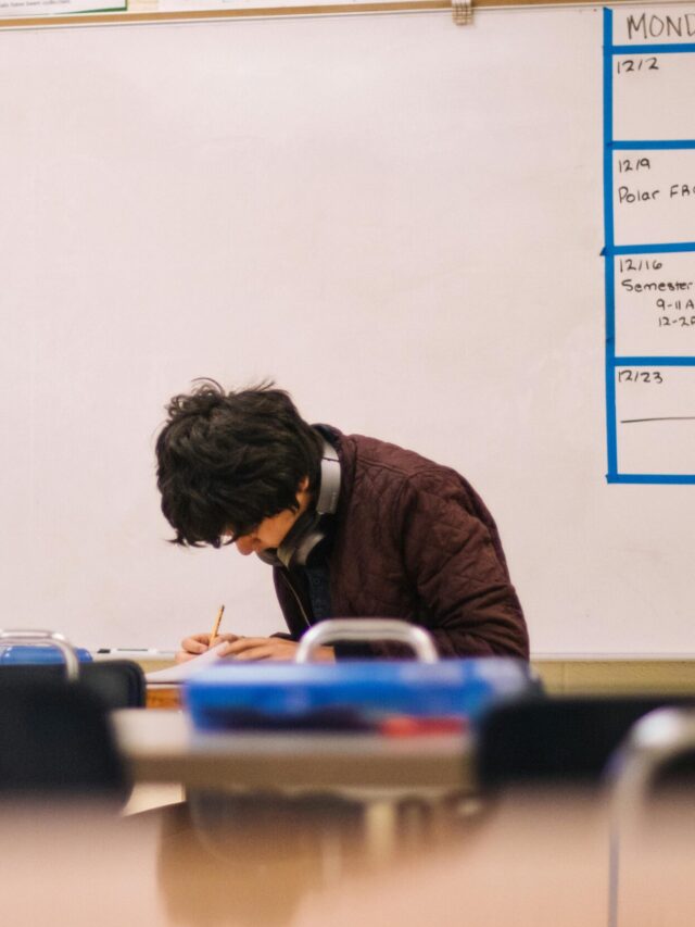 A high school student studying and solving problems in a classroom setting.