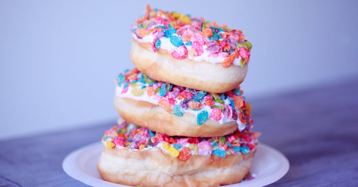 A stack of doughnuts covered in colorful fruity pebbles on a plate.