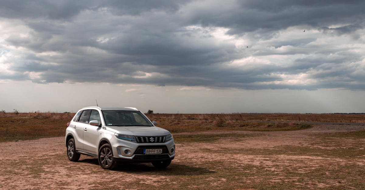 A silver SUV parked on a rural dirt path with dramatic cloud formations in the sky.