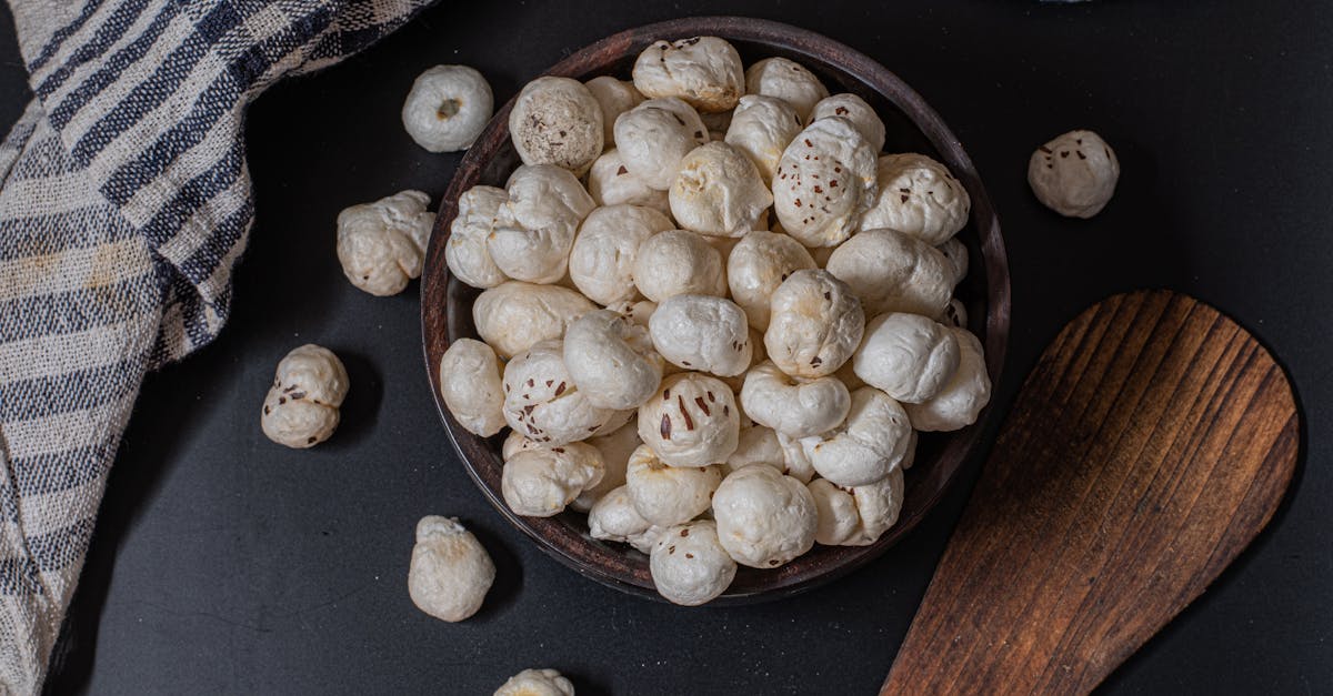 A rustic bowl filled with puffed lotus seeds on a black background, perfect for snacks.