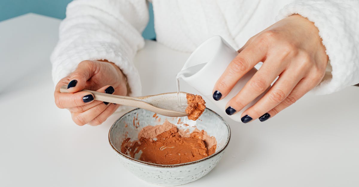 Close-up of a person mixing a natural clay mask with water for skincare.