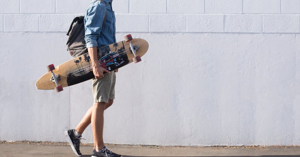 Casual young man walking with longboard against a white brick wall in Sanger, California.